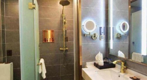 a bathroom with a sink and a shower with a mirror at James Joyce Coffetel Chengdu Jichang Road Shenxianshu in Chengdu