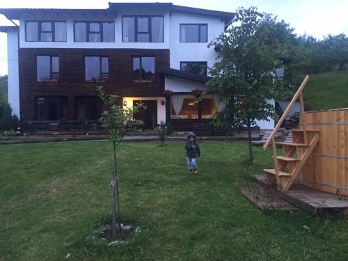 a young child standing in the yard of a house at Talhaus in Vişeu de Sus