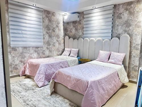 two beds in a bedroom with pink and grey wallpaper at Modern villa with pool and all comforts in Mendoza
