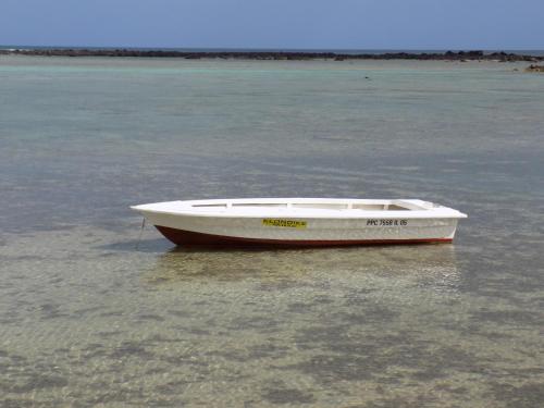 a white boat is sitting in the water at Villa Osumare Guest House in Flic-en-Flac