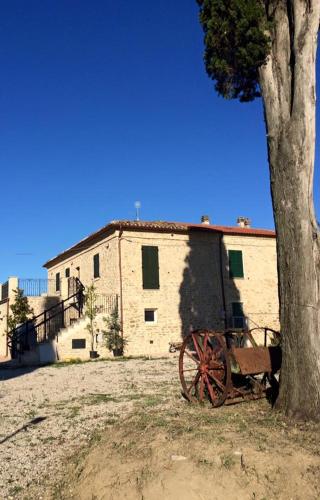 an old cart sitting under a tree next to a building at Azienda Agricola Perconti in Cellino Attanasio