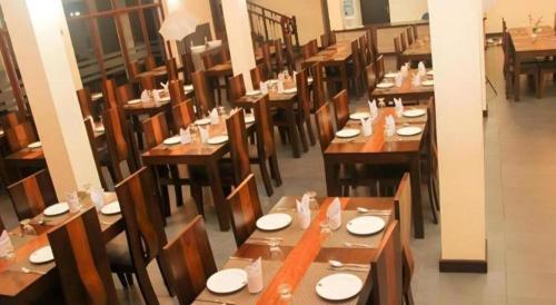 a restaurant with wooden tables and chairs with plates on them at Talawakele Rest House in Nuwara Eliya