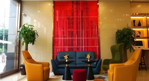 a lobby with chairs and a table and red curtain at Borrman Hotel Zhanjiang Shimao Building High-speed Railway Station in Zhanjiang