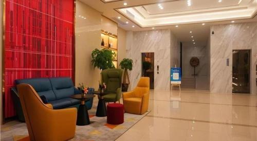 a lobby with chairs and tables in a building at Borrman Hotel Zhanjiang Shimao Building High-speed Railway Station in Zhanjiang