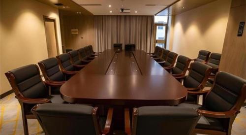 a conference room with a large wooden table and chairs at Echarm Hotel Zibo Gaoqing Zhongcheng Inernational in Zibo