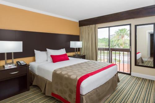 ボカラトンにあるHoliday Inn & Suites Boca Raton - Northの大きなベッドとバルコニーが備わるホテルルームです。