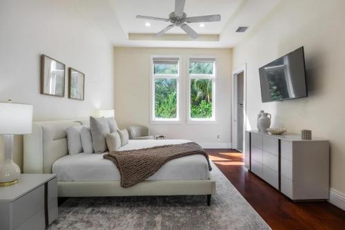 a white bedroom with a bed and a flat screen tv at New Luxe Super Villa by The Glam Homes in Plantation