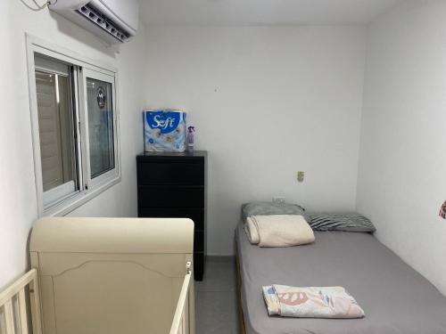 a small room with a bed and a window at פנטהאוז in Petaẖ Tiqwa