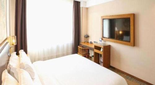 a hotel room with a bed and a television at James Joyce Coffetel Changchun People's Square in Changchun