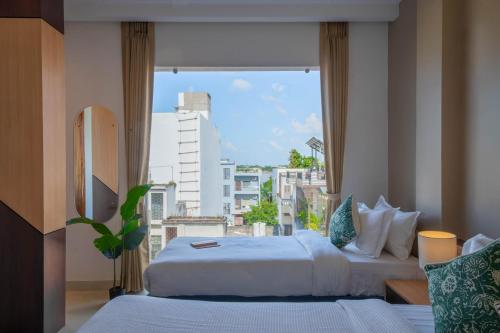 バラナシにあるKaashin - A Boutique Stayのベッドが2つと大きな窓がある寝室