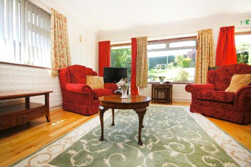 a living room with red chairs and a coffee table at Dean Court Garden - Parking - by Brighton Holiday Lets in Rottingdean