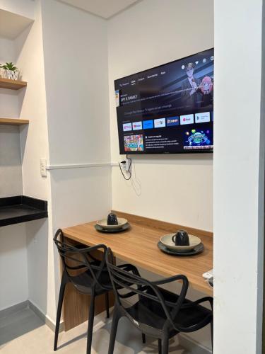una camera con tavolo, due sedie e una TV di Flat Moderno a 100m da Praia do Bessa a João Pessoa