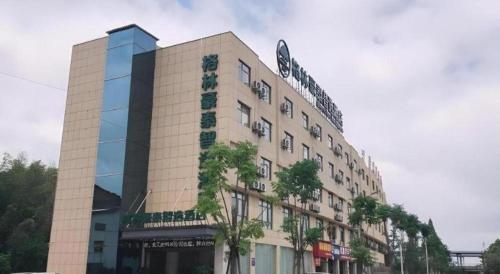 a large building with a tree in front of it at GreenTree Inn Express Yingtan Yujiang Railway Station in Yingtan