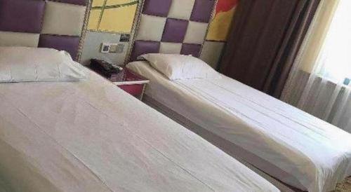 two twin beds in a room with a window at Ease Hotel Shanghai Chuanhuan Nan Road Chuansha Metro Station in Shanghai