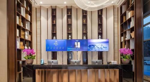 a lobby with a desk with laptops on it at VX Hotel Wuxi Xinwu District Executive Center Wanda Plaza in Wuxi