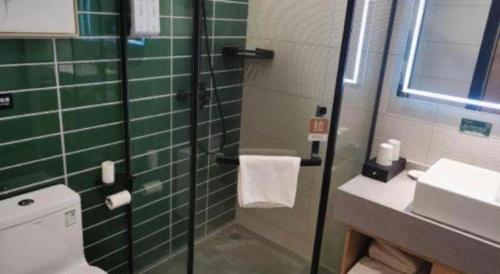 a green tiled bathroom with a shower and a sink at Green Tree Inn Fuyang Funan County Tianzhu Square in Funan