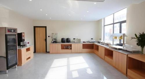 a large kitchen with wooden cabinets and a large window at GreenTree Inn Express Zhangjiagang Hexing Town Shazhou Professional Institue of Technology in Qiwei