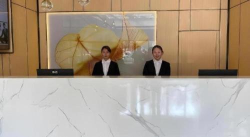 two women in suits are sitting at a table at GreenTree Inn Express Shandong Jinin Jiaxiang Railway Station in Jining