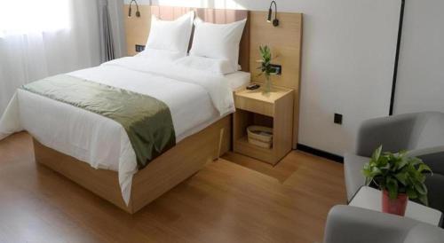 a bedroom with a large white bed and a chair at GreenTree Inn Express Datong High-Speed Railway Station Old City Wall in Datong