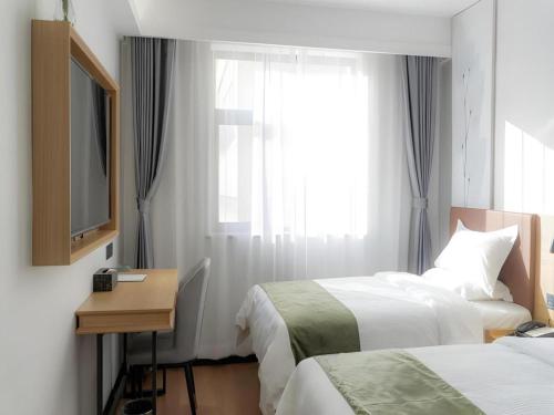 a hotel room with two beds and a desk and a window at GreenTree Inn Express Datong High-Speed Railway Station Old City Wall in Datong