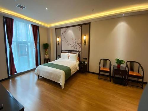 a hotel room with a bed and two chairs at GreenTree Inn Express Datong High-Speed Railway Station Wanda Plaza Fangte in Datong