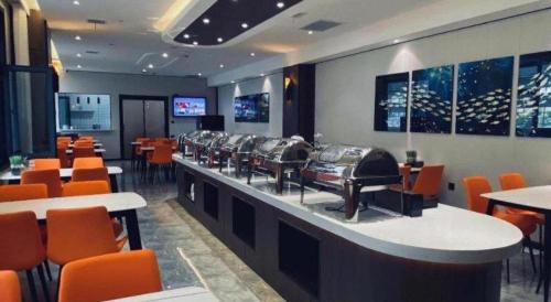 a restaurant with a bar with orange chairs at GreenTree Inn Express Datong High-Speed Railway Station Wanda Plaza Fangte in Datong