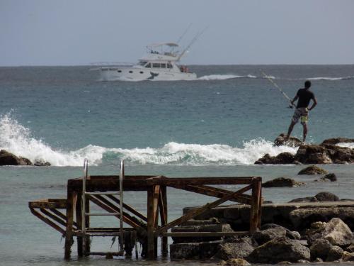 a man on the beach with a boat in the water at Villa Osumare Guest House in Flic-en-Flac