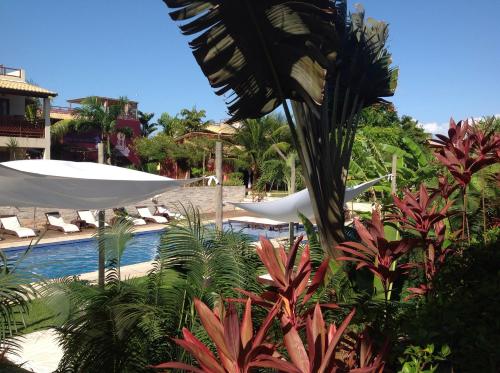a resort swimming pool with chairs and a white umbrella at Apartamento A-11 Pipa Beleza Resort in Pipa