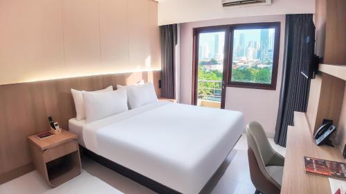 a hotel room with a white bed and a window at SHANKEE Sudirman in Jakarta