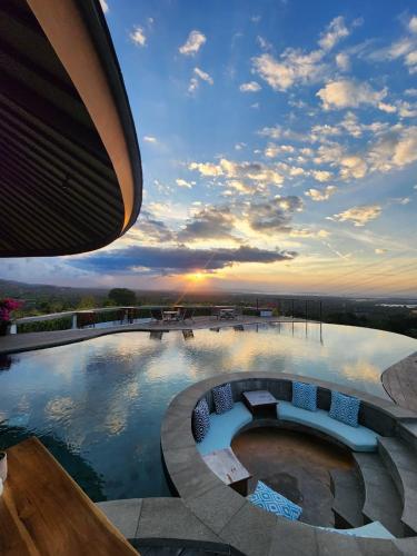 a large swimming pool with a sunset in the background at Sumberkima Resort in Pemuteran