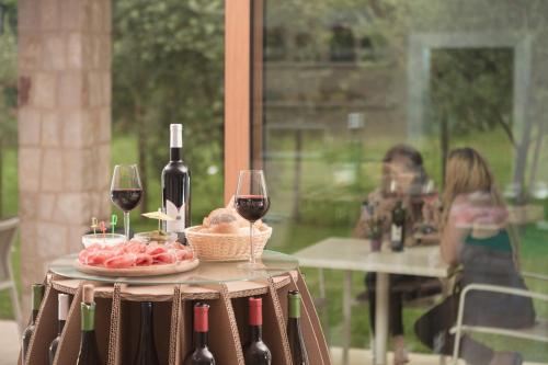 a table with two glasses of wine and a plate of food at Agriturismo Vin e Amor in Dro