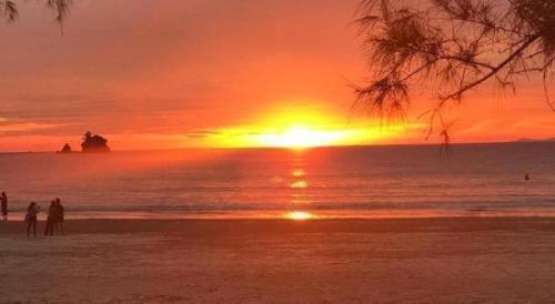 people standing on the beach watching the sunset at Longbeach Kohphayam in Ko Phayam