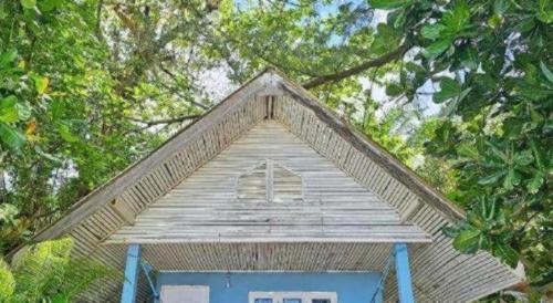 a small house with blue doors and trees at Longbeach Kohphayam in Ko Phayam