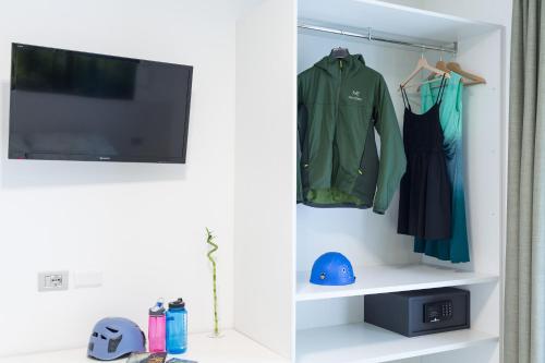 a room with a tv and a shelf with clothes at Agriturismo Vin e Amor in Dro