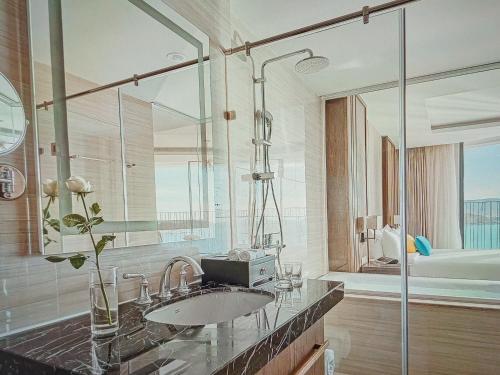 a bathroom with a sink and a glass shower at MELLIA OCEANUS NHA TRANG BAY Five-Star Suites in Nha Trang