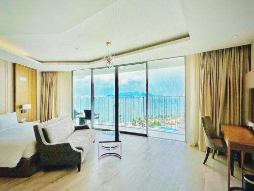 a bedroom with a bed and a desk and a large window at MELLIA OCEANUS NHA TRANG BAY Five-Star Suites in Nha Trang