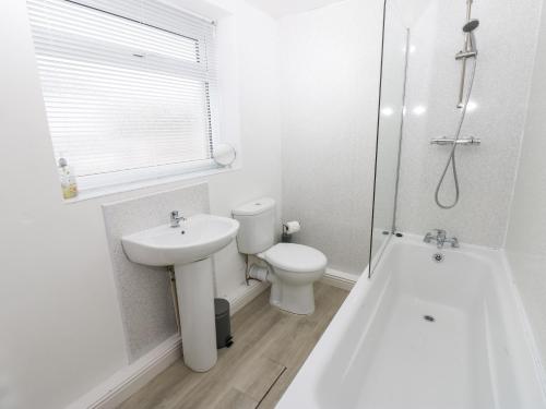 a white bathroom with a toilet and a sink at Holly House in Whitehaven