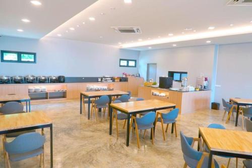 a restaurant with tables and chairs and a kitchen at Sans Hotel in Ratchaburi