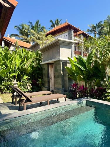 a swimming pool with a bench and a house at Puri Diamond Villas in Tampaksiring