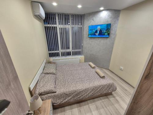 a small bedroom with a bed and a tv on the wall at Apartment The Garden in Ruse