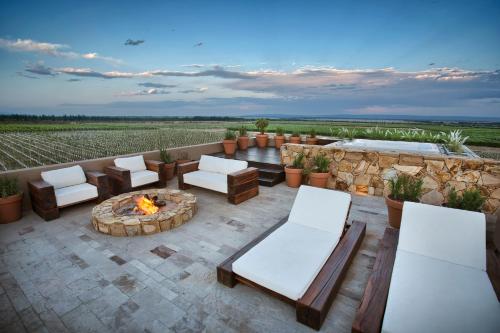 a patio with a fire pit and chairs and a stone wall at Rosell Boher Winery Lodge & Spa in Agrelo