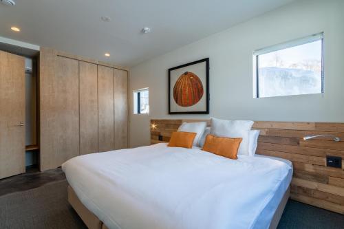 a bedroom with a large white bed with orange pillows at Foxwood D in Niseko