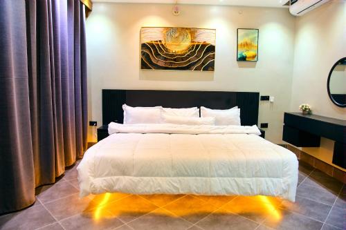 a bedroom with a large white bed with purple curtains at Bhai Apartments in Mwanza