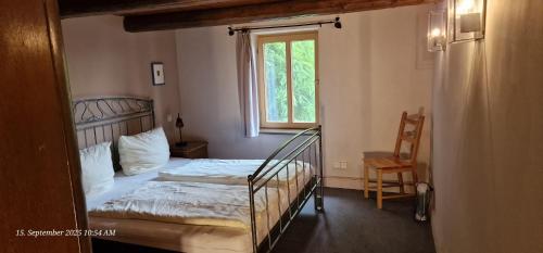 a bedroom with a bed and a window and a chair at Pension Robinienhof in Schadeleben