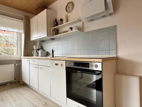 Una cocina con gabinetes blancos y un horno. en Haus Moby Dick, en Wangerooge