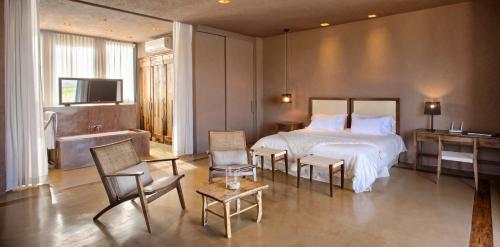a bedroom with a bed and chairs and a television at Rosell Boher Winery Lodge & Spa in Agrelo