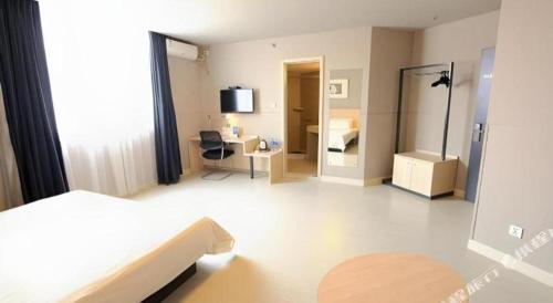 a bedroom with a bed and a desk and a mirror at Jinjiang Inn Quanzhou West Street Kaiyuan Temple in Quanzhou
