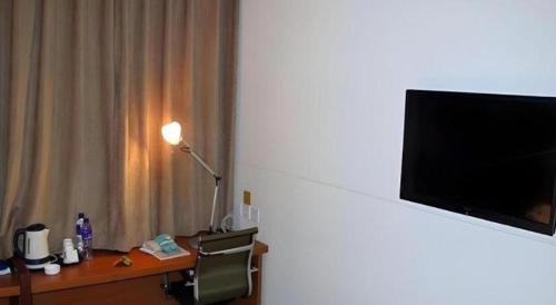 a room with a desk with a television on a wall at Jinjiang Inn Style Shenyang The Palace Huaiyuan Gate in Shenyang