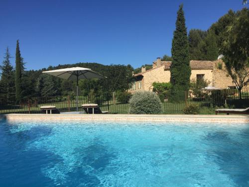 une piscine avec une table et un parasol dans l'établissement La Ferme Des Belugues, à Le Barroux
