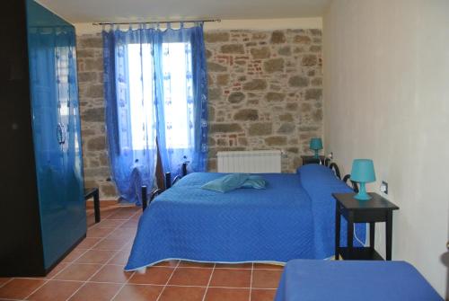 Un dormitorio con una cama azul y una pared de ladrillo en Il Vicolo, en Tortorici